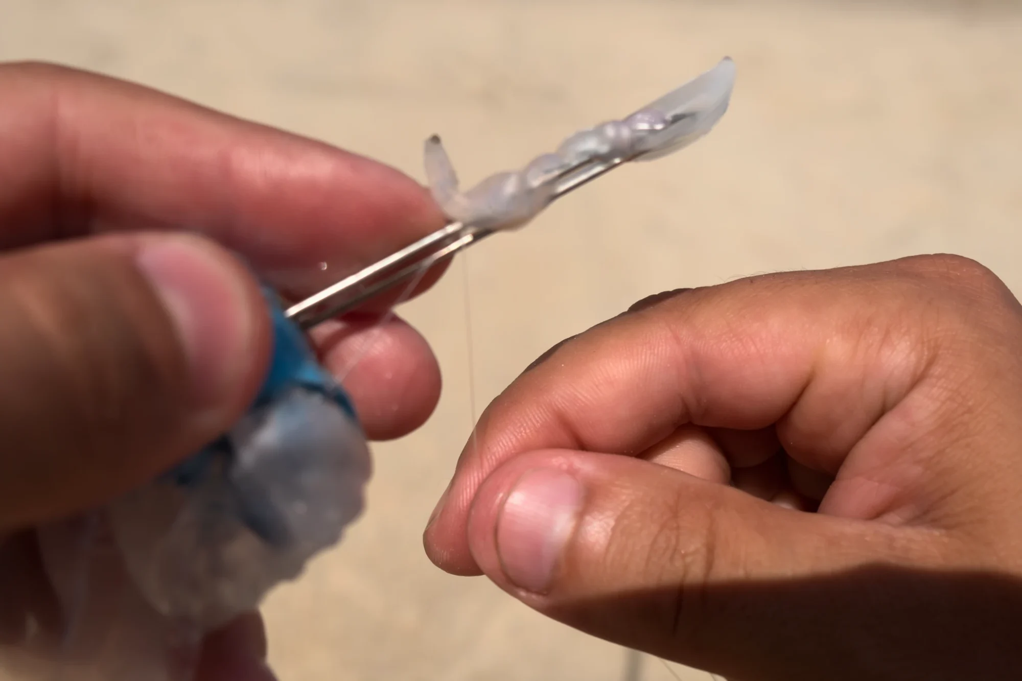 manos enrollando hilo elástico en un cebo apoyado en las agujas del ELASTCASE 2x1